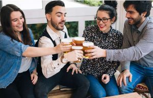 Young group of friends having fun in a bar toasting with beer